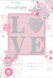 In this image, an anniversary card is presented like a small work of romantic art, its design built around the gentle glow of blush pinks and shimmering silvers. The background is a soft, even pink that recalls the colour of early spring blossoms in gardens around Wandsworth. At the very centre, the word LOVE emerges in large, raised letters, generously dusted with fine glitter so that each stroke glints delicately when light touches the surface. The texture is visibly three-dimensional, as if you could feel every line and contour under your fingertips. Encircling this central word is a graceful arrangement of stylised flowers, slender leaves, and curling stems, drawn with refined, sweeping lines that resemble a florist's outline for a romantic hand-tied bouquet. The petals are shaded in pale blush, off-white, and cool grey, with occasional silver highlights that sparkle like tiny droplets of water on fresh blooms. These motifs drift outward, forming soft arcs and swirls that balance the composition while keeping the focus on the central declaration of love. Between the floral elements, subtle scrolls and patterns add depth without cluttering the design. A heartfelt anniversary message, printed in a flowing script that feels as intimate as a handwritten note, appears above and below the main motif, its fine strokes echoing the curves of the florals. The overall mood is one of enduring affection and gentle celebration, perfectly suited to mark years of shared life, just as thoughtfully as an anniversary bouquet delivered to a doorstep off Trinity Road.